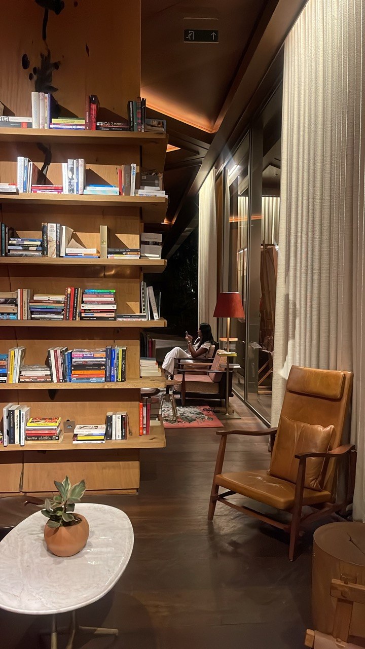 Espaço de hotel com biblioteca e poltronas