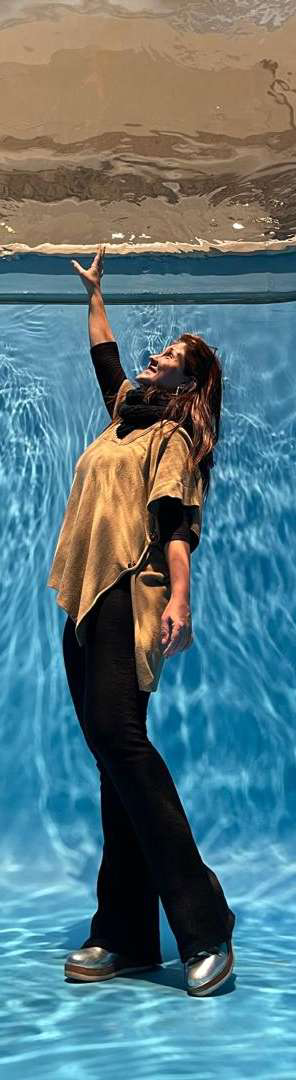 Laura Brunello em uma piscina, com a mão tocando a superfície da água